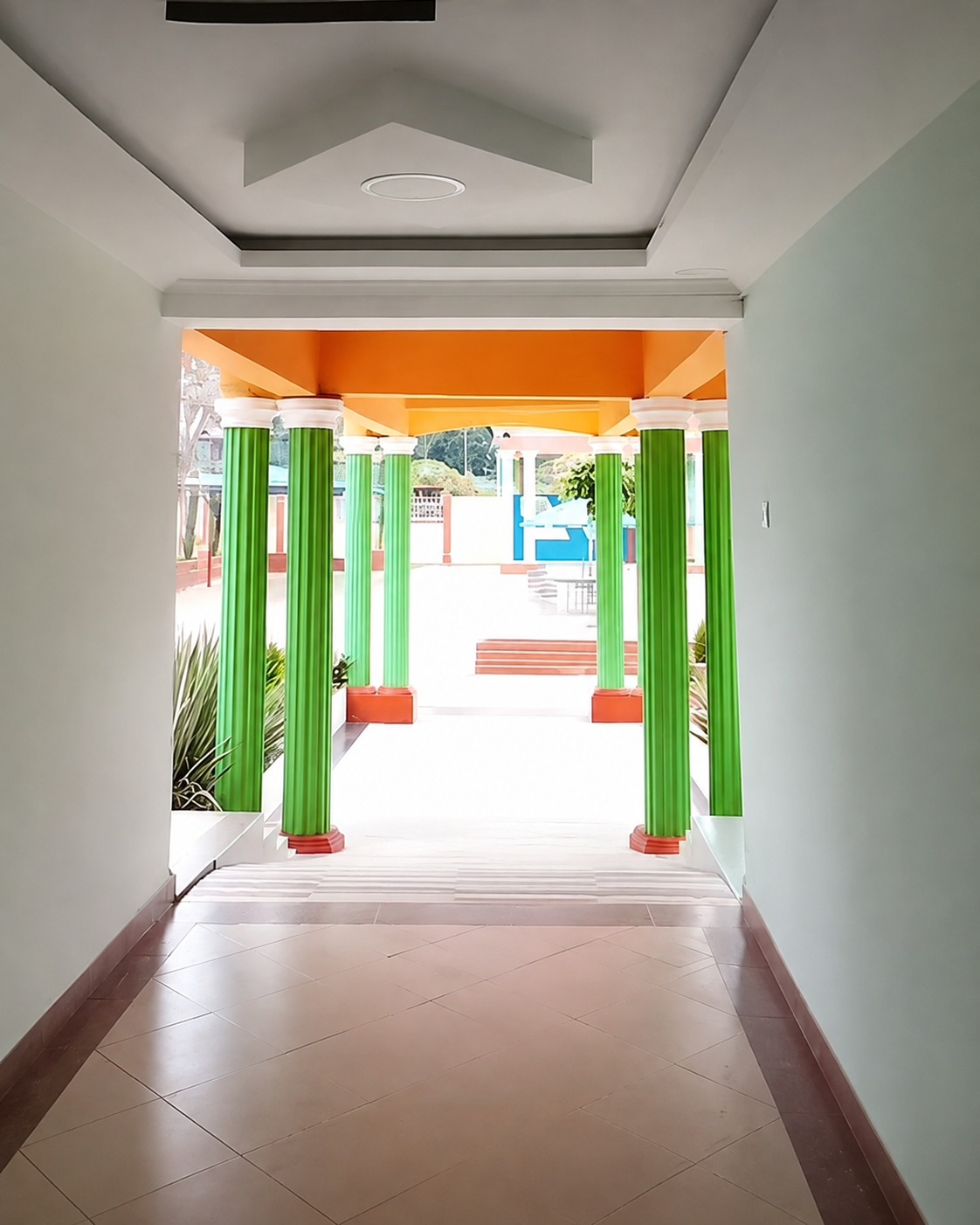 Interior corridor at Cool Breeze Funeral Home looking out to the green-columned covered walkway and forecourt