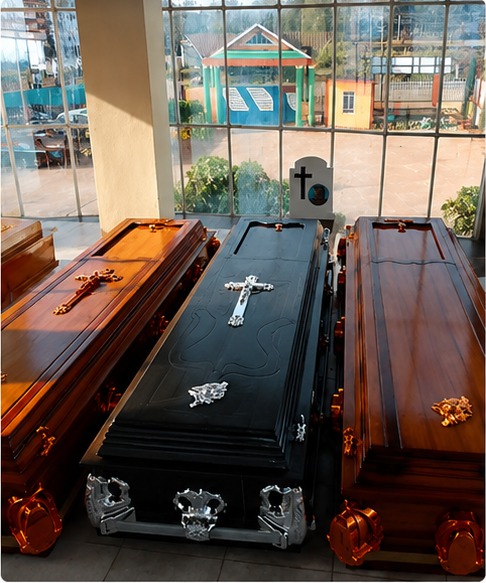 A black coffin with a silver crucifix between two polished mahogany coffins with gold fittings