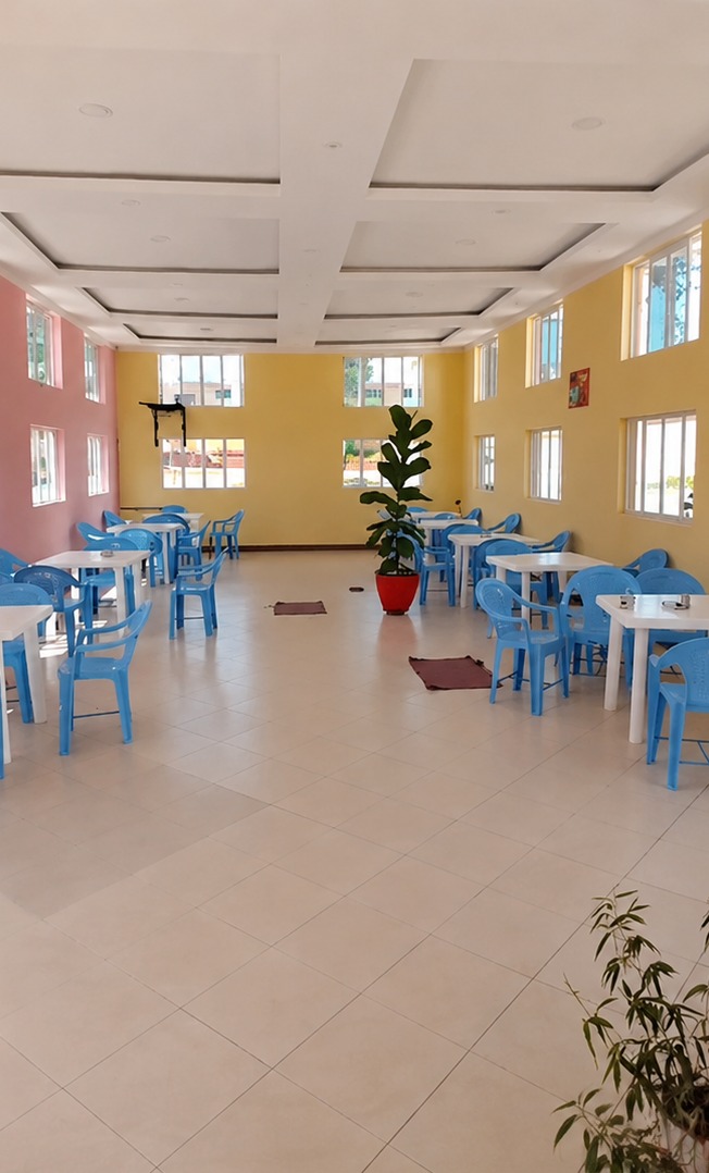 The bright cafeteria hall at Cool Breeze Funeral Home, with blue chairs, white tables and tall windows