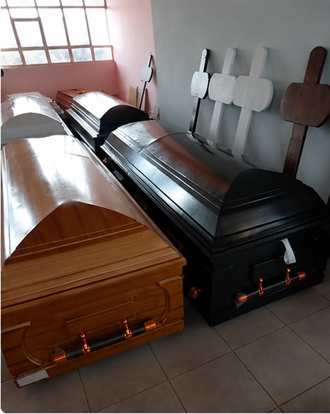 A curved-lid timber coffin beside a dark polished coffin in the showroom