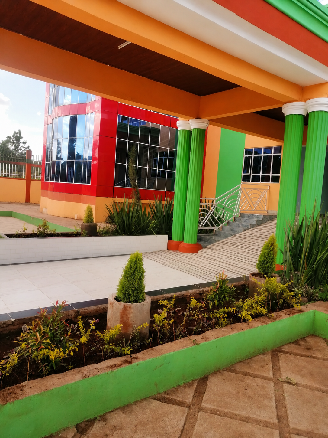 The covered entrance walkway at Cool Breeze Funeral Home, with green columns, tiled paving and landscaped flower beds